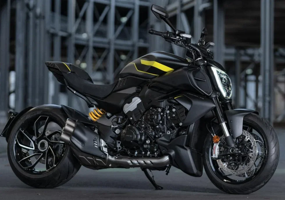 Moto Ducati Diavel V4 S noire avec détails jaunes, vue de profil, sur fond industriel