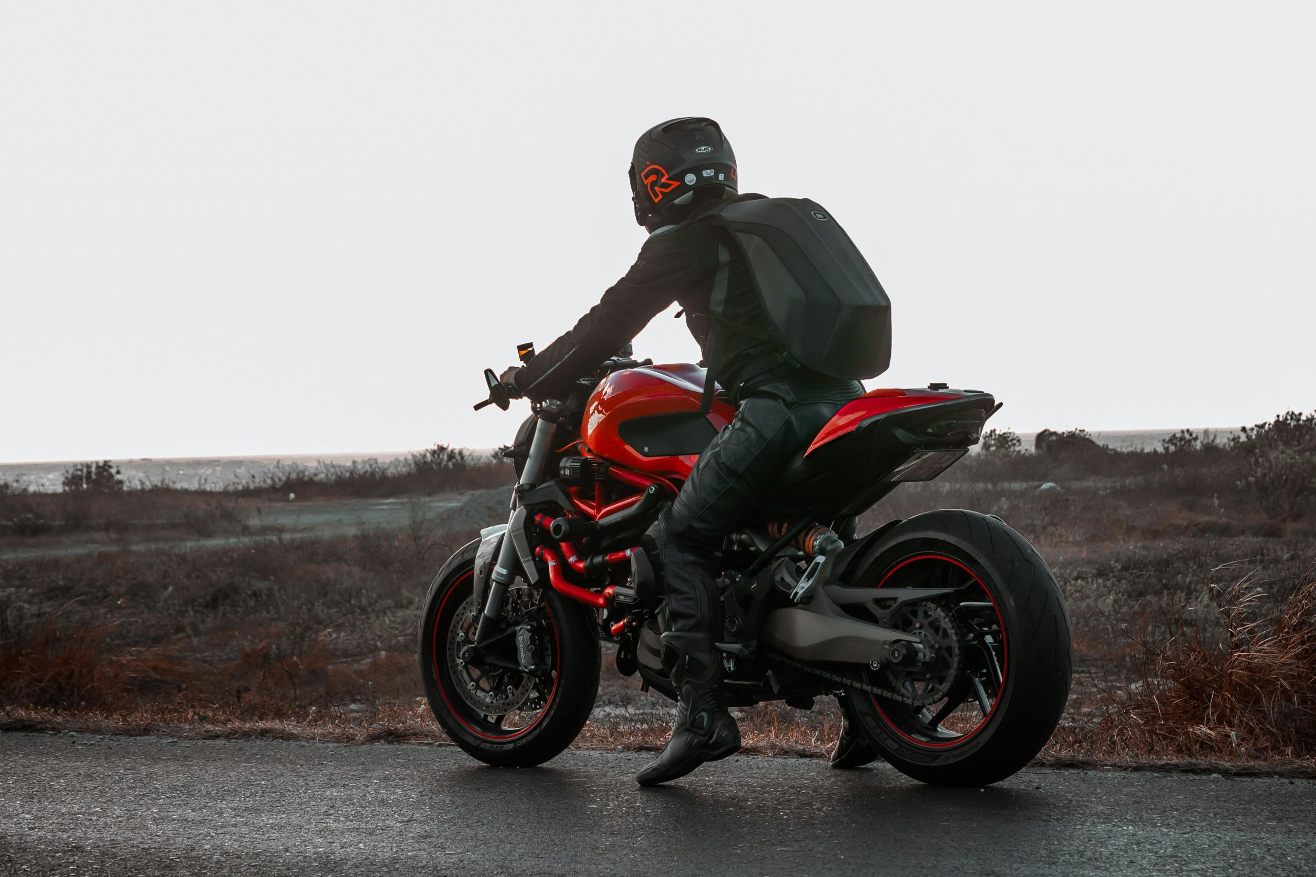 A motorcyclist in gear rides a red Ducati on an open road, showcasing speed and adventure.